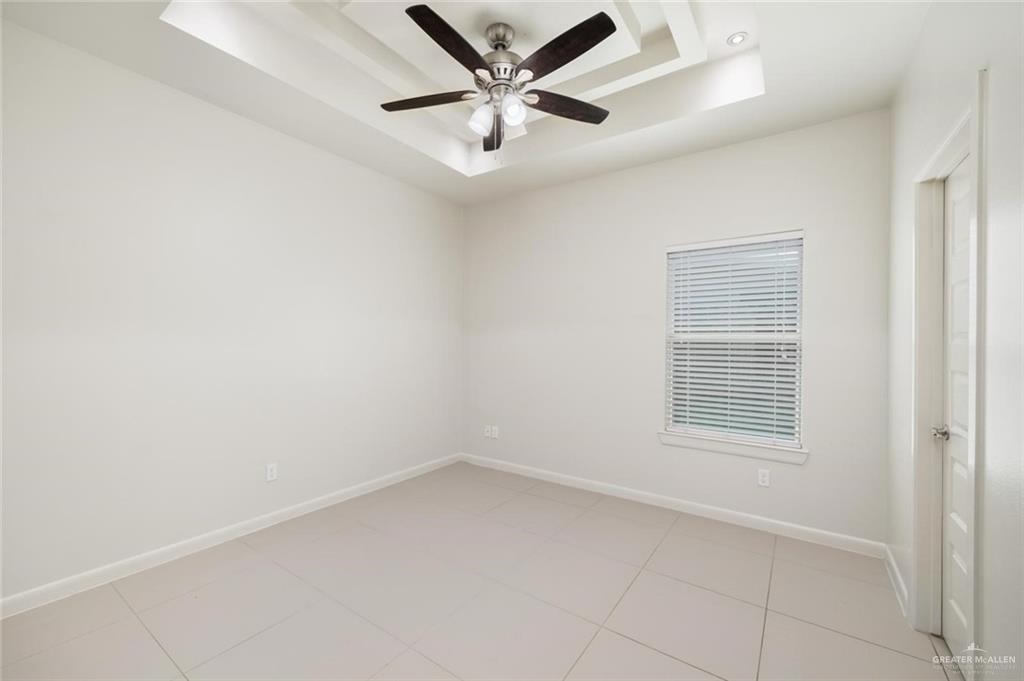 1716 West Garrison Drive, Unit 2 Pharr, TX 78577 - Photo 6 of 17 Empty room with a raised ceiling, light tile patterned flooring, and a ceiling fan