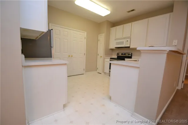 a kitchen with granite countertop white cabinets and white appliances