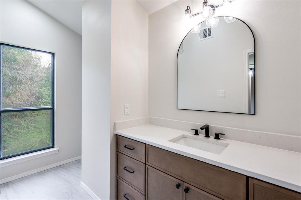 17490 Meandering Way, Unit 2202 Dallas, TX 75252 - Photo 23 of 24 Modern vanity featuring wood-finish cabinetry, a white countertop, and a rectangular undermount sink with a matte black faucet