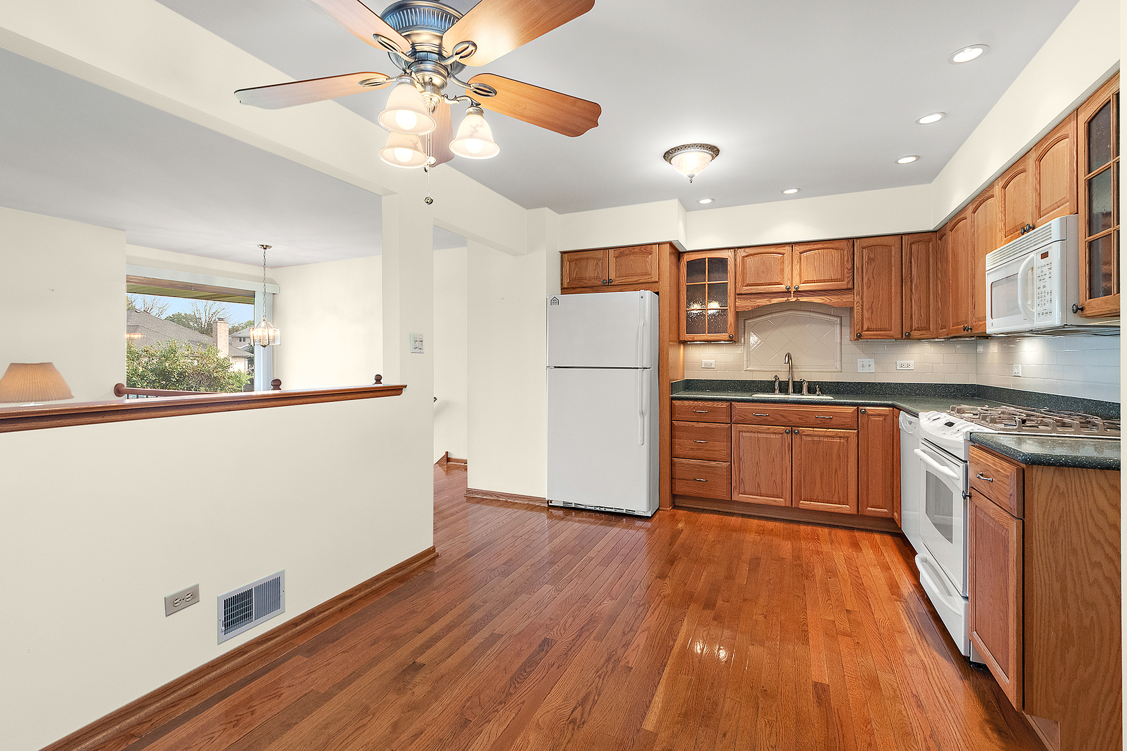 10459 Eagle Ridge Drive, Unit 139 Orland Park, IL 60467 - Photo 10 of 25 a kitchen with stainless steel appliances granite countertop a refrigerator a stove a sink and white cabinets with wooden floor next to windows