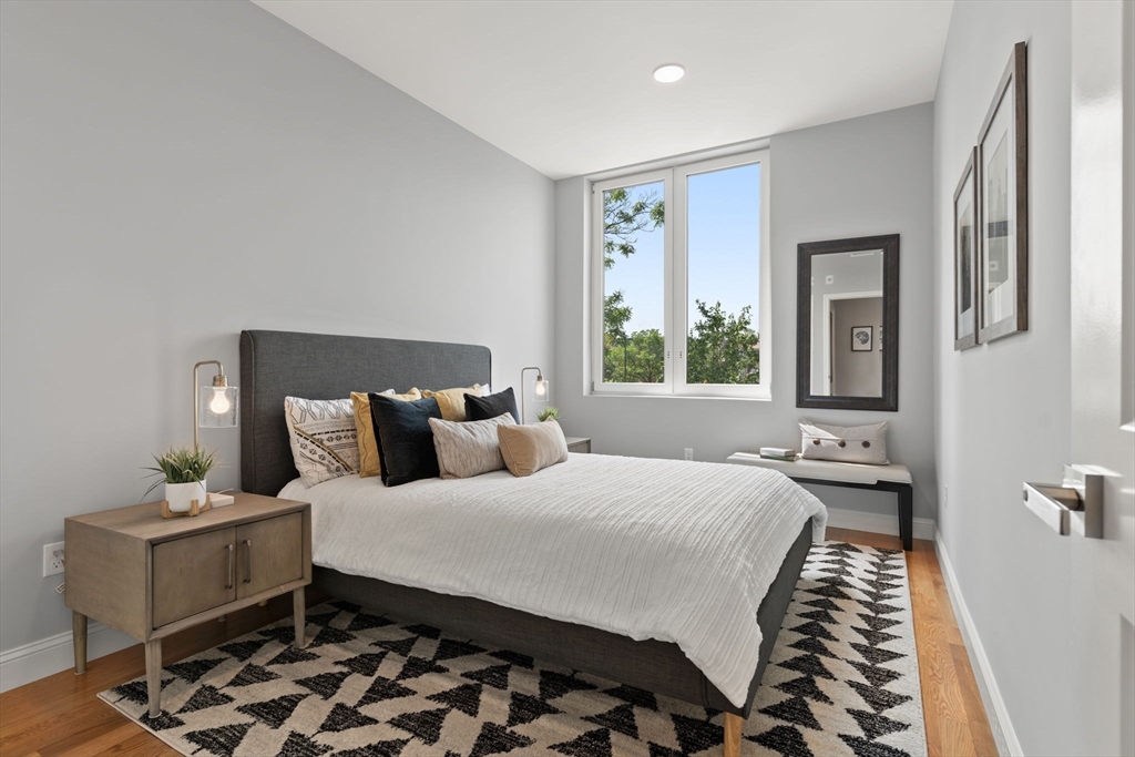 10 Taber Street, Unit 503 Boston, MA 02119 - Photo 12 of 21 a bedroom with a bed and wooden floor