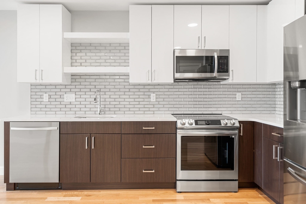 10 Taber Street, Unit 503 Boston, MA 02119 - Photo 3 of 21 a kitchen with stainless steel appliances wooden cabinets and a sink
