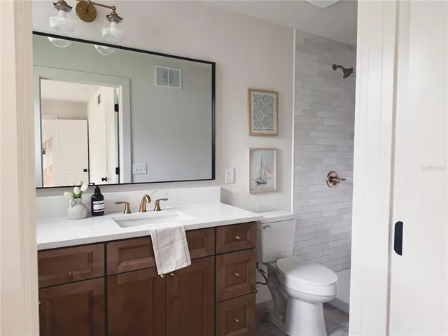 a bathroom with a double vanity sink toilet and mirror