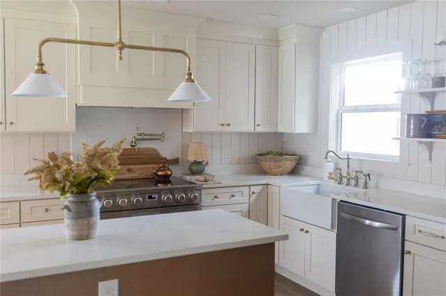 a kitchen with stainless steel appliances granite countertop a sink a stove and white cabinets