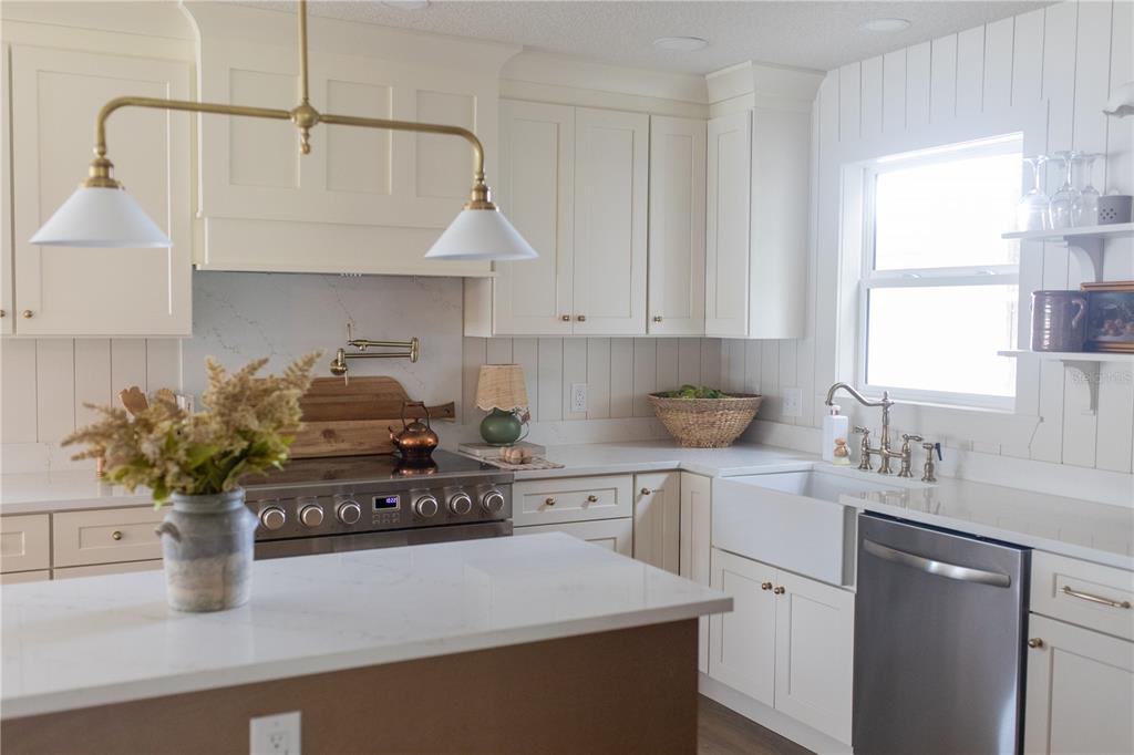 320 Rodeo Road Ormond Beach, FL 32174 - Photo 10 of 53 a kitchen with stainless steel appliances granite countertop a sink a stove and white cabinets