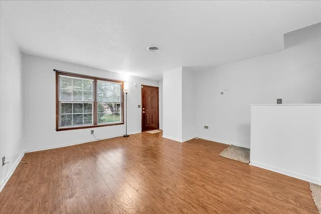 a view of an empty room with a window and wooden floor