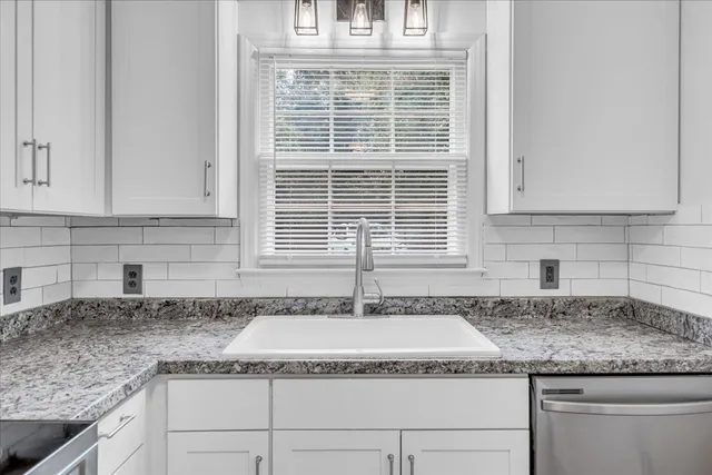 a kitchen with granite countertop white cabinets and a window