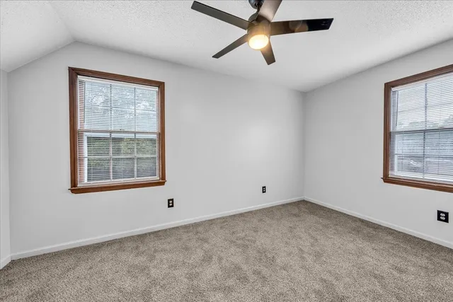 an empty room with a window and a fan