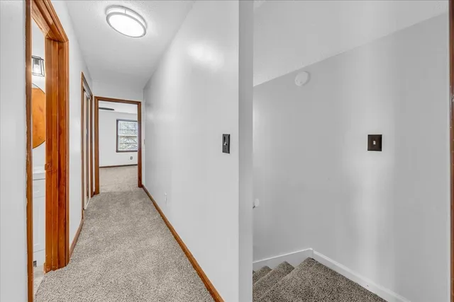 a view of a hallway with wooden floor and a bathroom