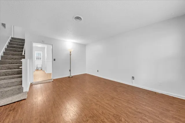 a view of empty room with wooden floor and windows