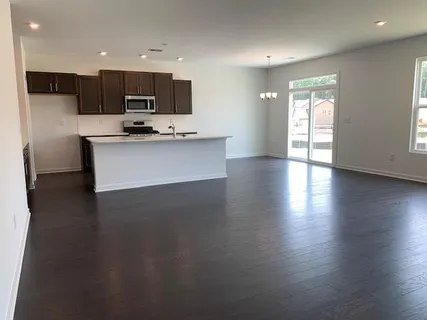 a view of kitchen with stainless steel appliances granite countertop a stove a sink a refrigerator white cabinets and wooden floor