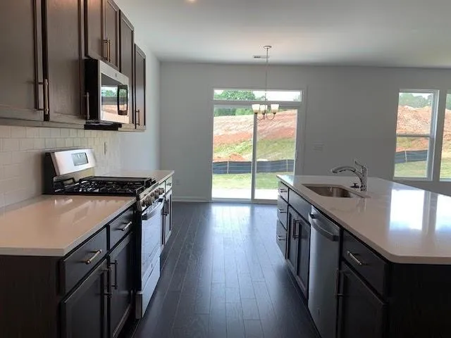 a kitchen that has a sink a stove and wooden floor