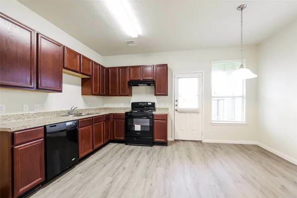 a kitchen with granite countertop wooden floors a stove and a microwave