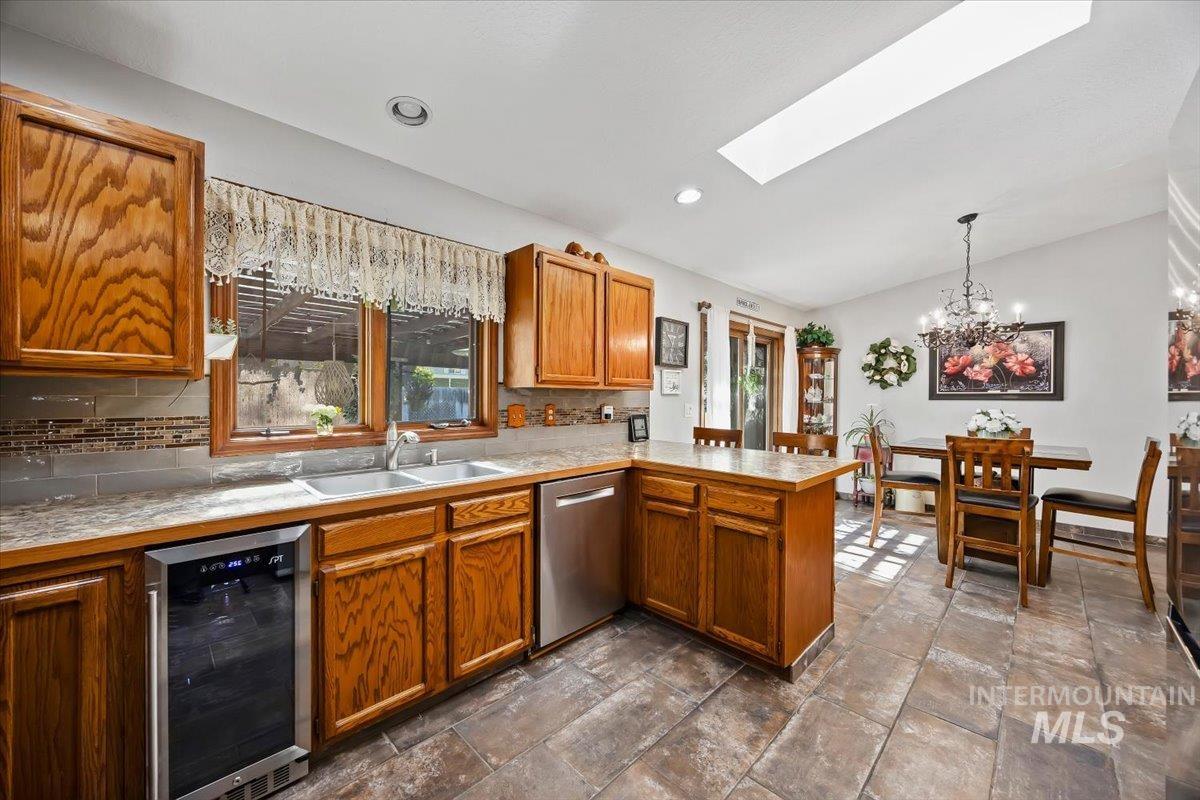 956 Bitterroot Place Twin Falls, ID 83301 - Photo 11 of 48 Kitchen featuring rich wood cabinetry, stainless steel appliances including a built-in wine cooler and dishwasher, a tile backsplash, and a double basin sink