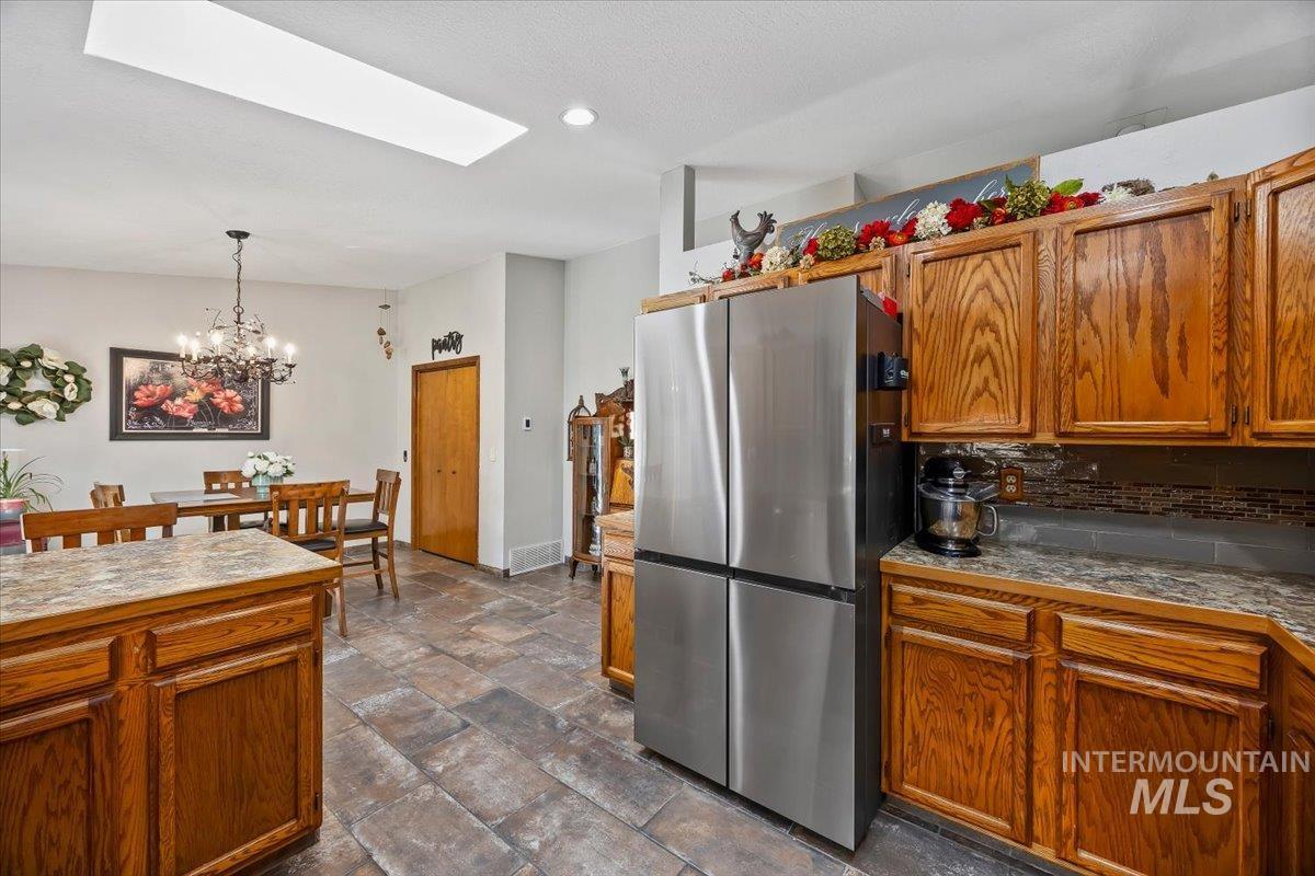 956 Bitterroot Place Twin Falls, ID 83301 - Photo 13 of 48 Kitchen featuring wood cabinetry, a stainless steel refrigerator, and stone-look tile flooring