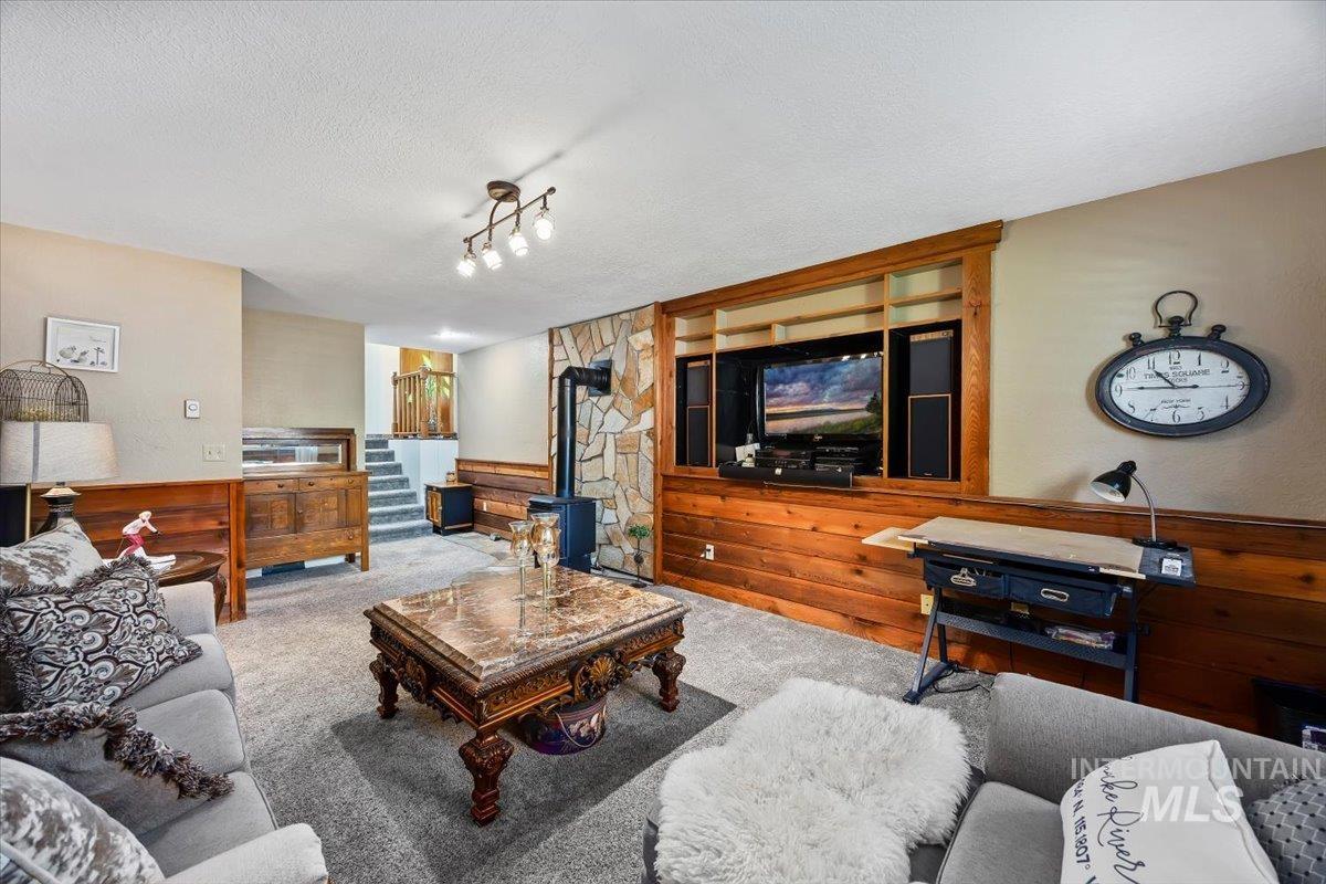 956 Bitterroot Place Twin Falls, ID 83301 - Photo 16 of 48 Spacious living area featuring a built-in media center with wood-finish paneling, a stone-accented wall with an attached stove, and recessed shelving