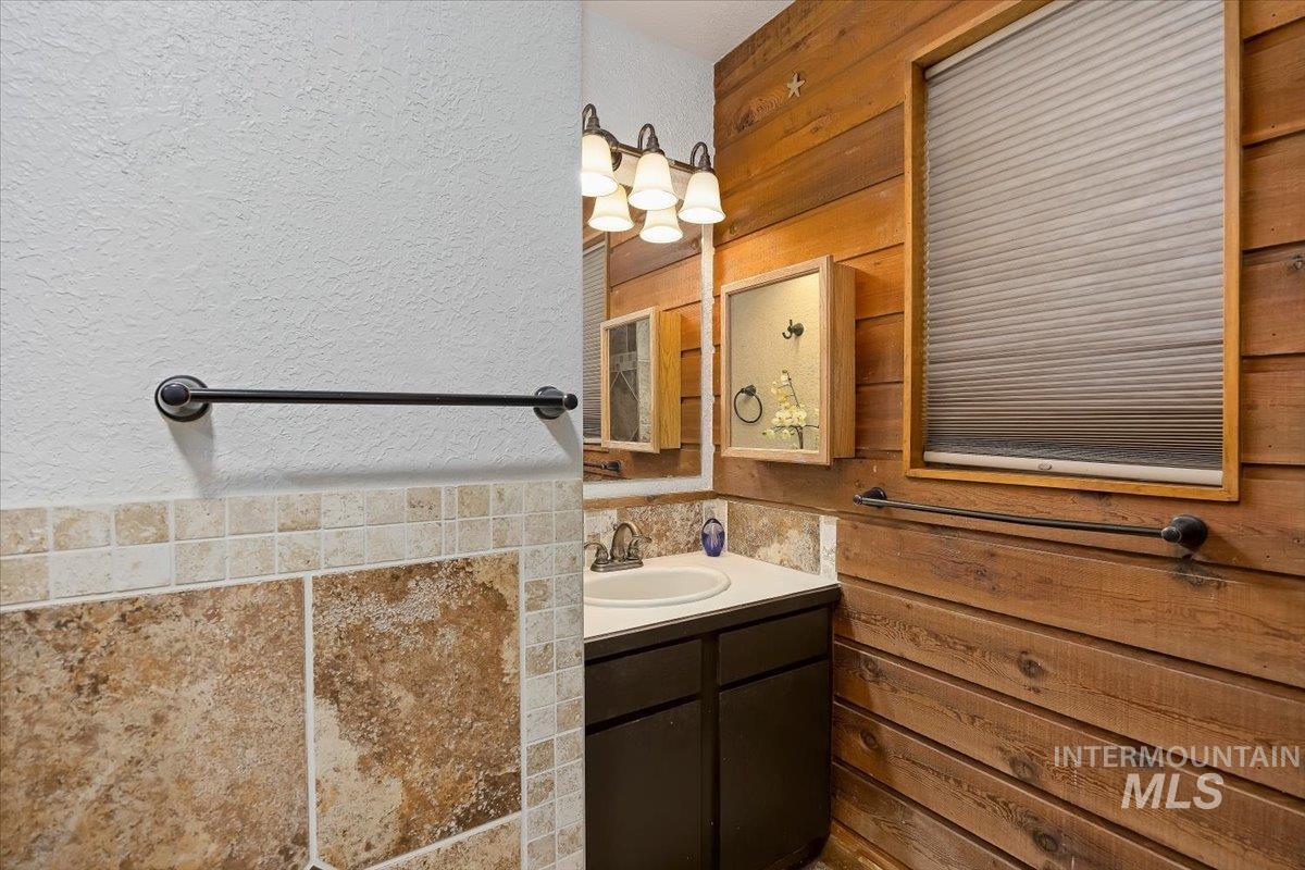 956 Bitterroot Place Twin Falls, ID 83301 - Photo 19 of 48 Bathroom featuring wood-finish paneling, a single-sink vanity with a light countertop, and a window with blinds