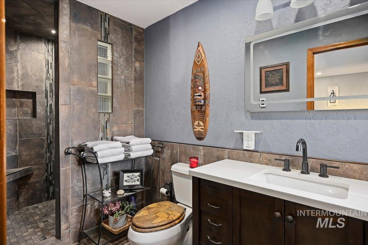 956 Bitterroot Place Twin Falls, ID 83301 - Photo 24 of 48 Bathroom featuring a vanity with a white countertop and rectangular sink, dark wood-finish cabinetry, and a black faucet