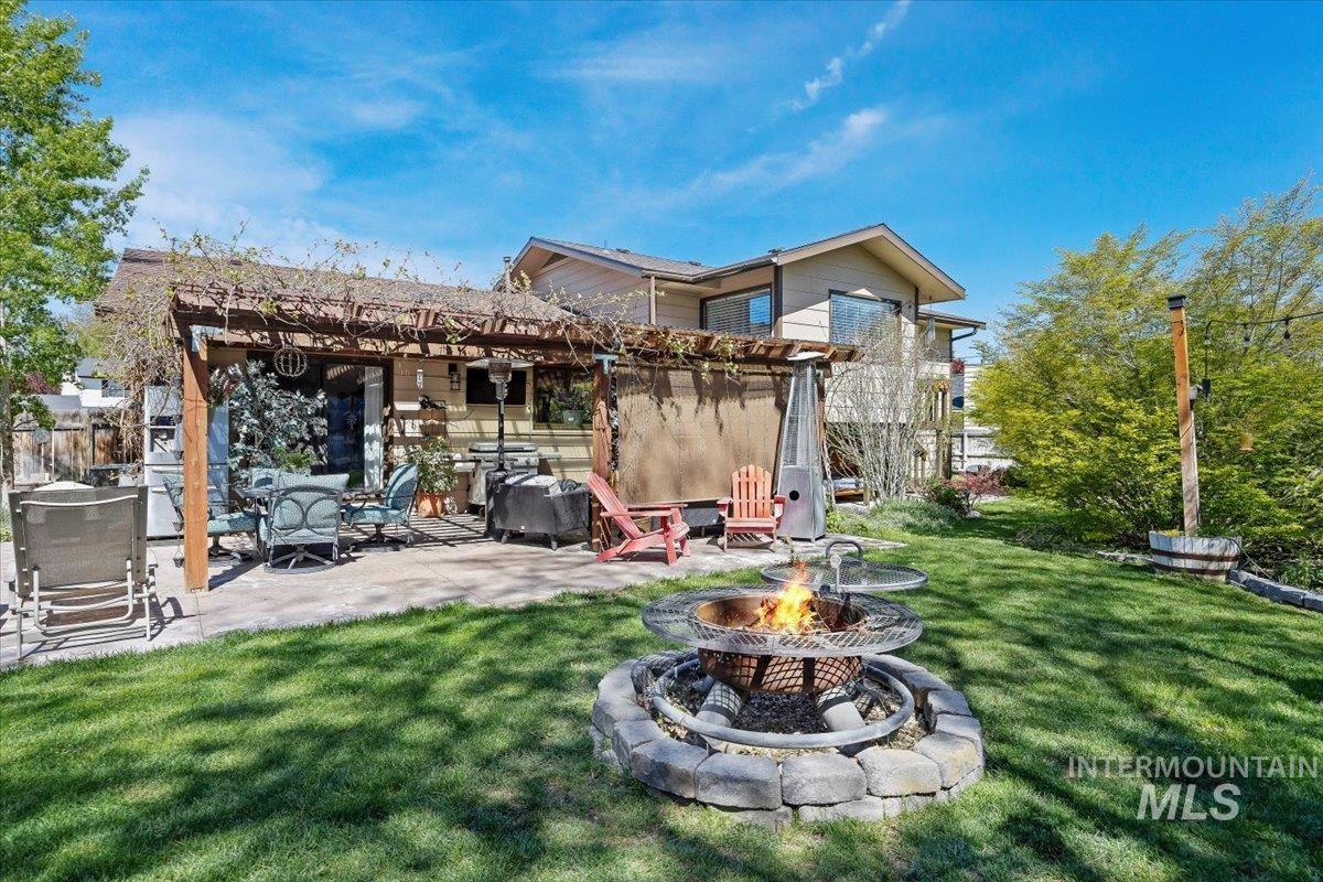 956 Bitterroot Place Twin Falls, ID 83301 - Photo 31 of 48 Expansive backyard featuring a stone-lined fire pit, manicured lawn, and a pergola-covered patio with paver stone flooring