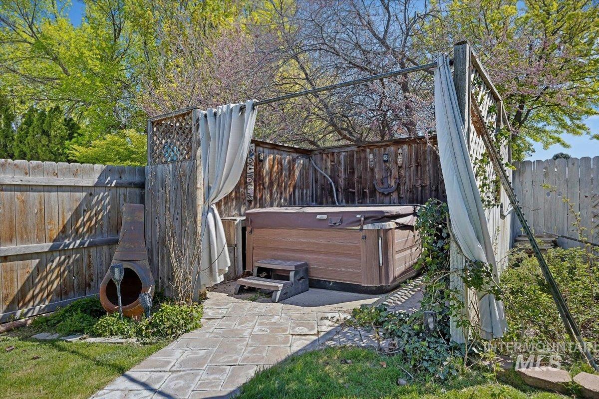 956 Bitterroot Place Twin Falls, ID 83301 - Photo 32 of 48 Outdoor spa area featuring a built-in hot tub with wooden surround, a stone paver patio, and a privacy screen with drapes