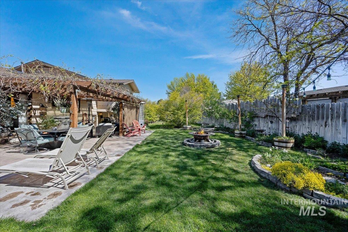 956 Bitterroot Place Twin Falls, ID 83301 - Photo 33 of 48 Expansive backyard featuring a stone fire pit, a wood pergola, a manicured lawn, tiered landscaping with stone retaining walls, and mature trees