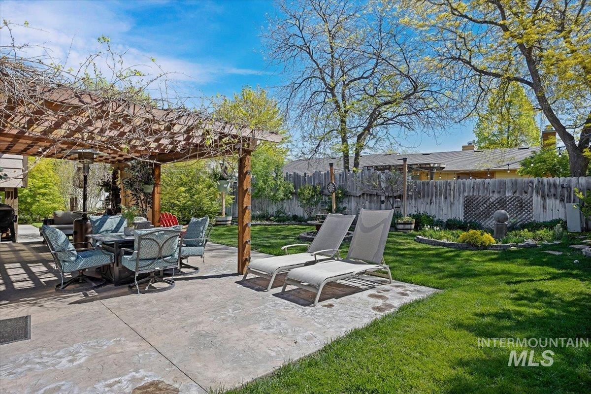 956 Bitterroot Place Twin Falls, ID 83301 - Photo 34 of 48 Expansive backyard featuring a concrete patio with a wooden pergola, mature greenery, and a manicured lawn