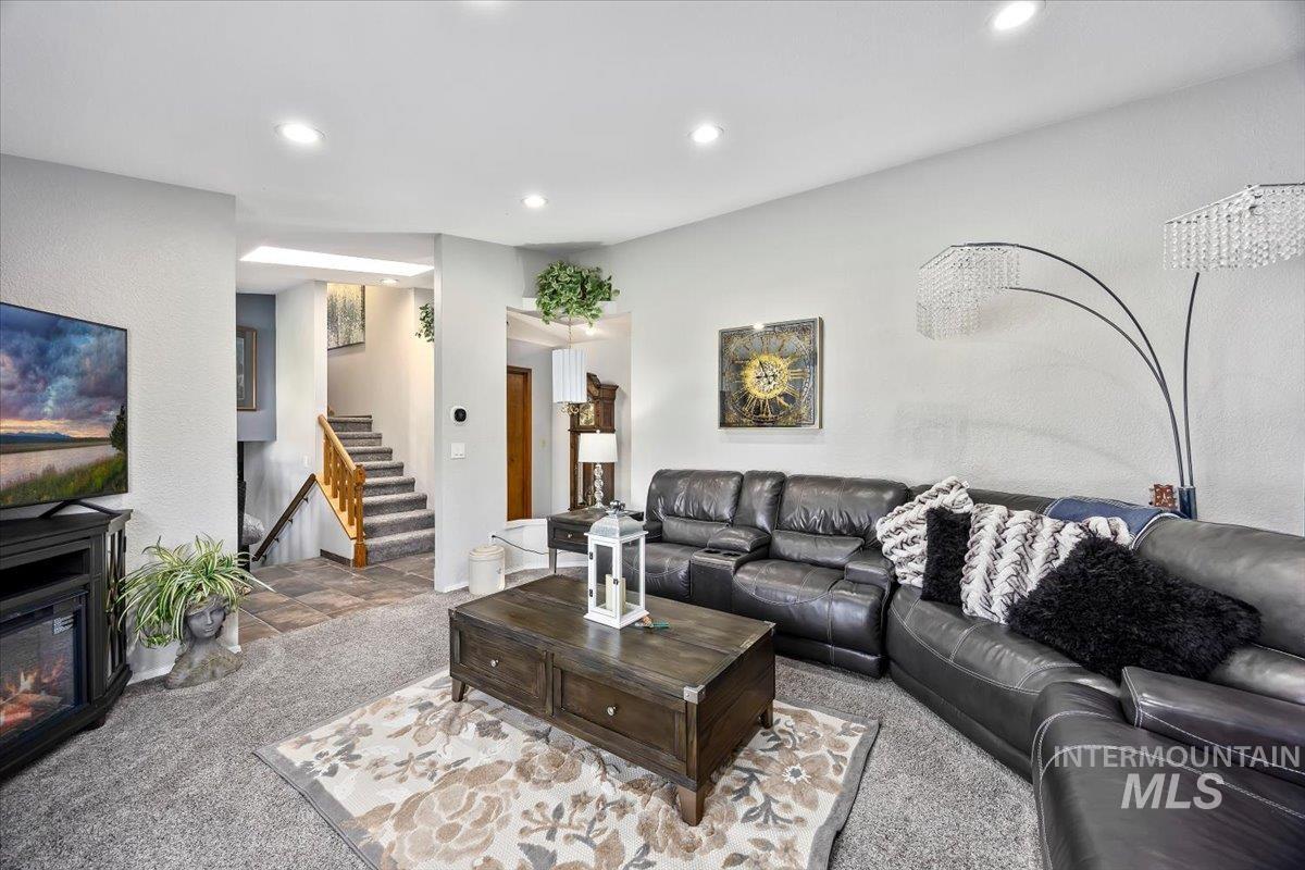 956 Bitterroot Place Twin Falls, ID 83301 - Photo 5 of 48 Living area featuring recessed lighting, a built-in electric fireplace, carpeted flooring, and a multi-level staircase with wood railings