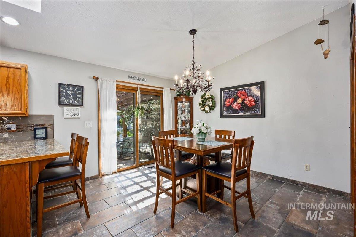 956 Bitterroot Place Twin Falls, ID 83301 - Photo 6 of 48 Dining area with large format tile flooring, a chandelier light fixture, and sliding glass door access to the outdoors