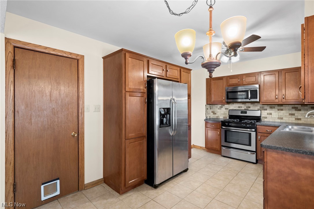227 South Messner Road New Franklin, OH 44319 - Photo 24 of 44 Kitchen with ceiling fan with notable chandelier, sink, stainless steel appliances, and backsplash