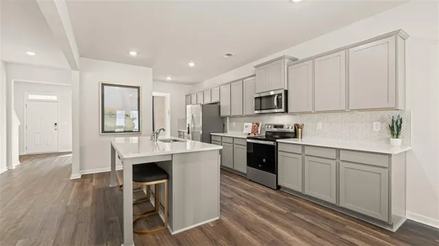 a kitchen with stainless steel appliances kitchen island granite countertop a stove a sink and a refrigerator