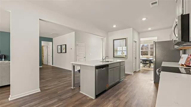 a large kitchen with stainless steel appliances granite countertop a lot of counter space and wooden floor