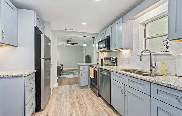 a kitchen with a sink wooden floor and stainless steel appliances