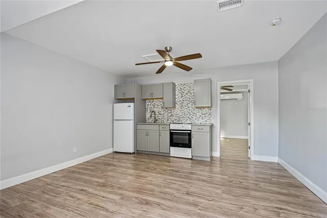 a view of kitchen and empty room with wooden floor