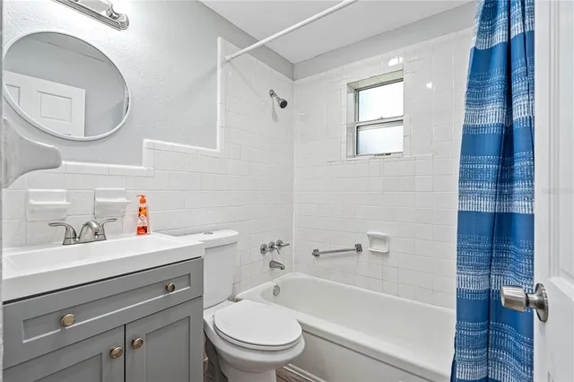 a bathroom with a toilet sink vanity tub and mirror