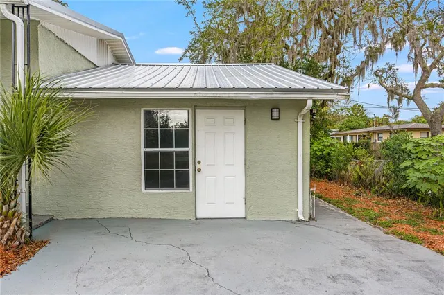 a view of a house with a yard and potted plants