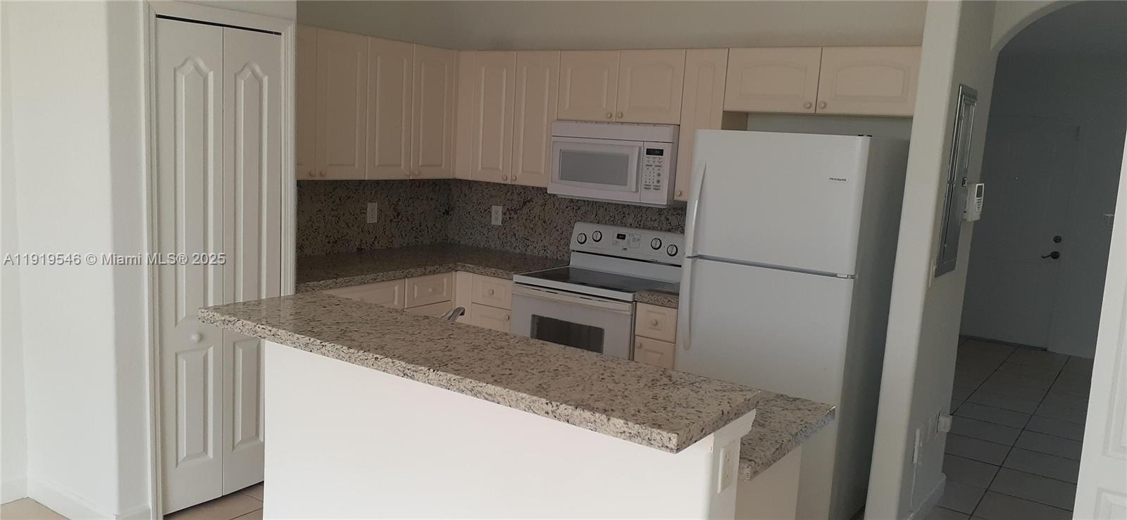 8091 West 36th Avenue, Unit 3 Hialeah, FL 33018 - Photo 6 of 16 a kitchen with granite countertop a refrigerator and a sink