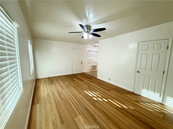 a view of a room with wooden floor and a ceiling fan
