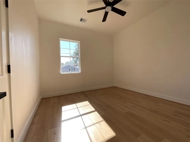 a view of empty room with wooden floor and fan