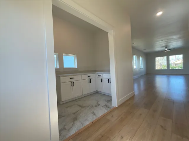 a view of a hallway to an empty room and window
