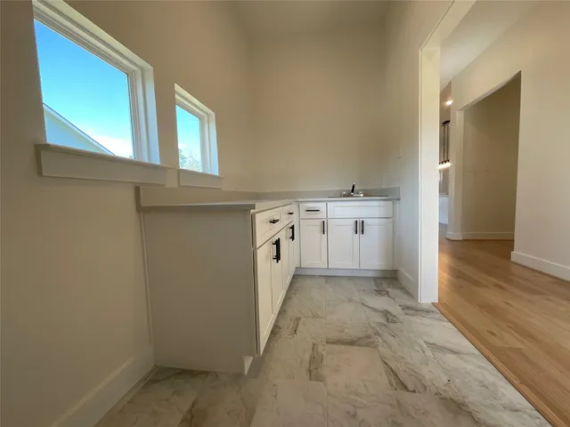 a view of a hallway with white cabinets and wooden floor