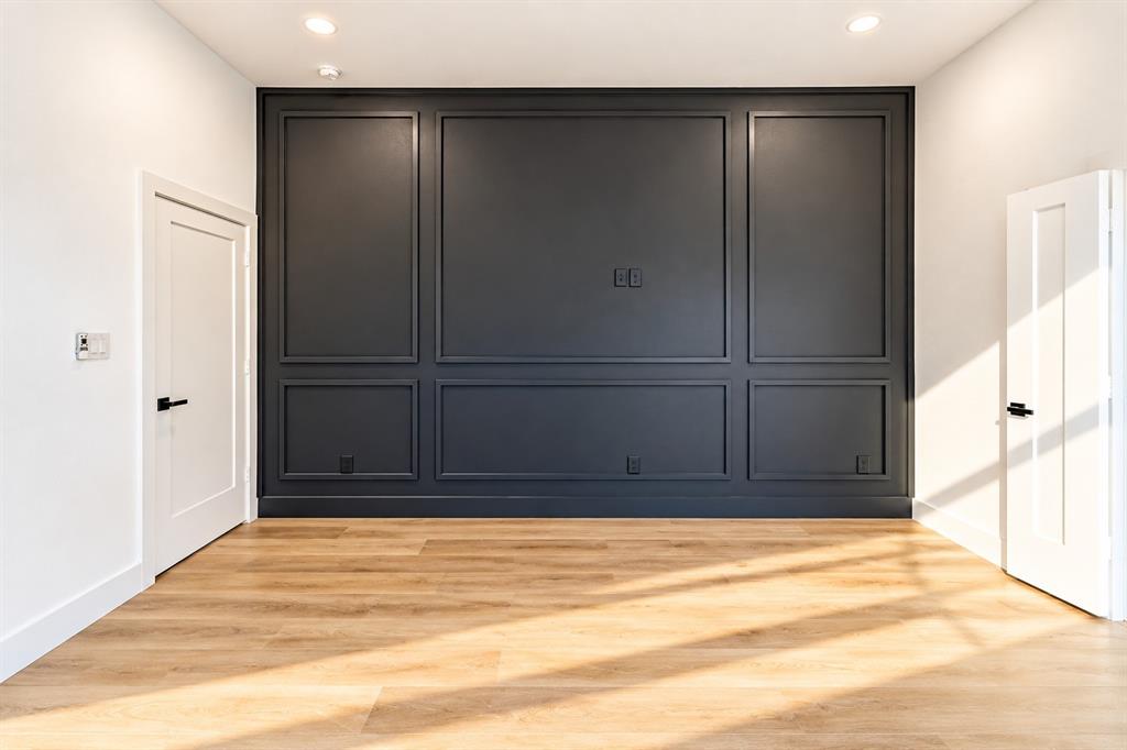 1640 West Wintergreen Road Lancaster, TX 75134 - Photo 16 of 37 Accent wall with panel molding, wood-finish flooring, recessed lighting, and white interior doors with black hardware