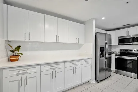 a kitchen with stainless steel appliances granite countertop white cabinets and a window