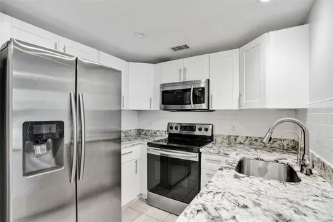 a kitchen with granite countertop a refrigerator stove and sink
