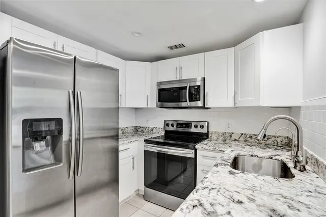 a kitchen with granite countertop a refrigerator stove and sink
