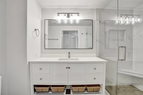 a bathroom with a sink shower and a mirror