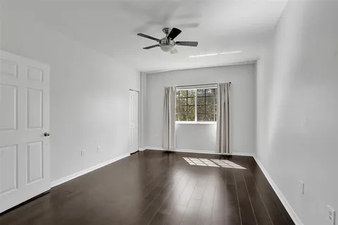 an empty room with wooden floor and a ceiling fan