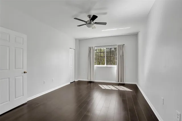 an empty room with wooden floor and a ceiling fan