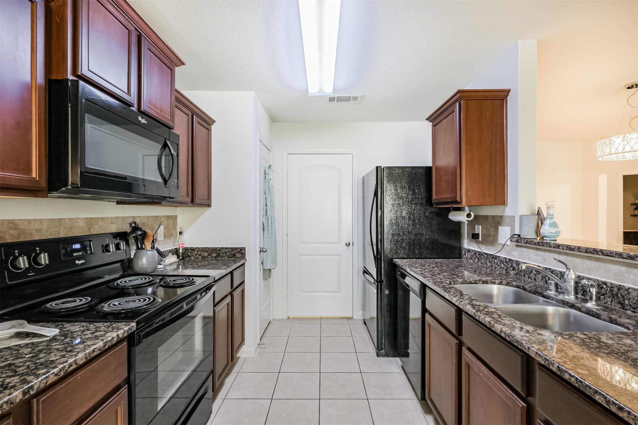 9438 Gold Mountain Drive Rosharon, TX 77583 - Photo 6 of 25 a kitchen with stainless steel appliances granite countertop a stove microwave refrigerator and sink