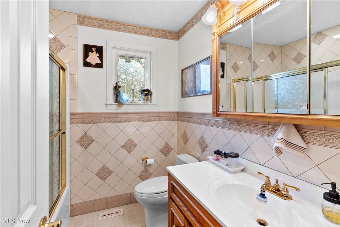 6810 South Ridge Road West Geneva, OH 44041 - Photo 18 of 41 Bathroom with an enclosed shower, vanity, tile walls, and wainscoting
