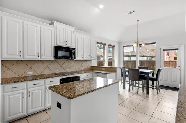 a kitchen with granite countertop white cabinets dining table and chairs